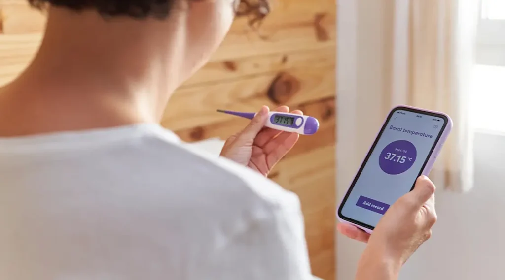 lady using fertility tracker to check her basal body temperature