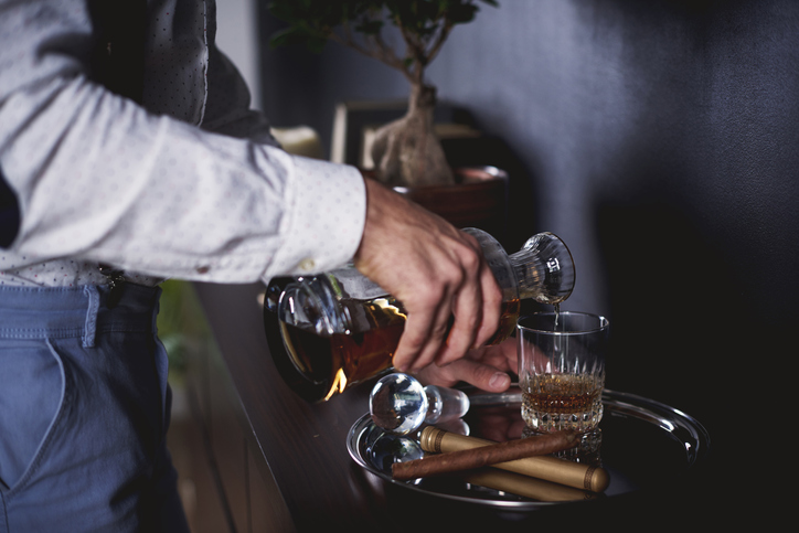 young man pouring alcohol into a glass cup