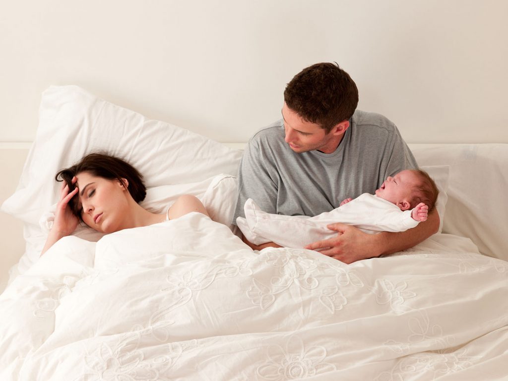young man carrying a baby while staring at his wife