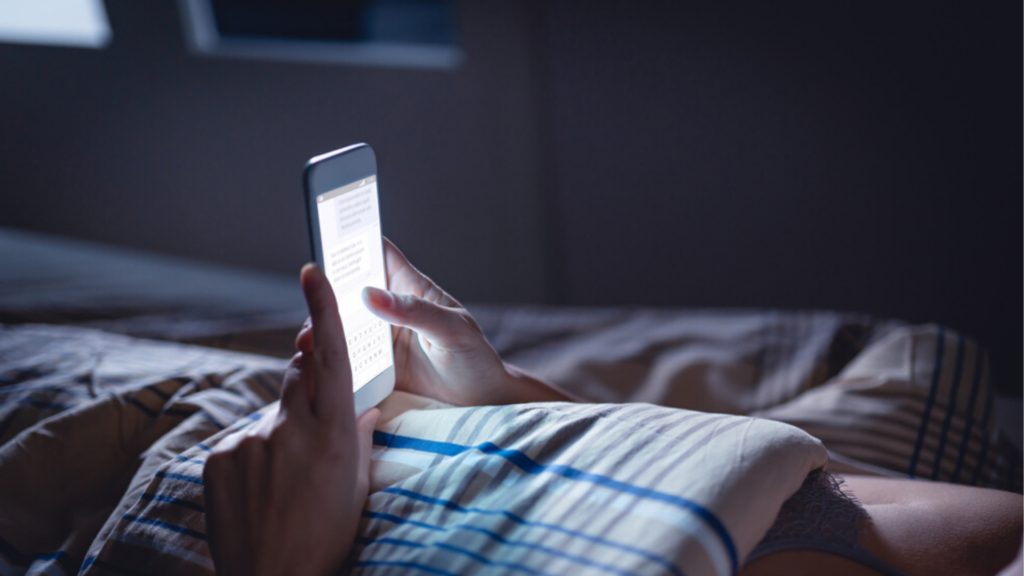 a man holding his phone while on bed