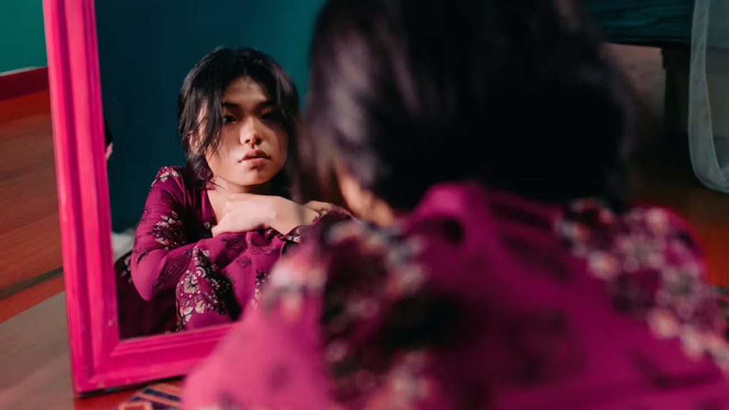 Woman looking at her reflection in the mirror, feeling depressed
