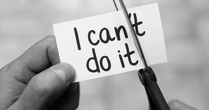man cutting a card written "I can't do it"