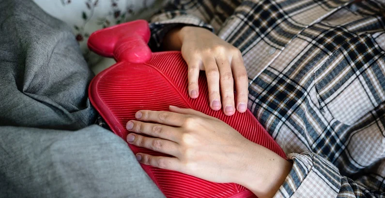 woman placing a heat bag on her stomach