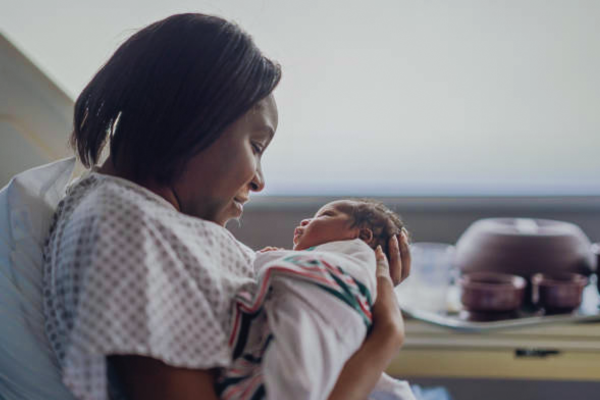 young woman on hospital wear holding a baby