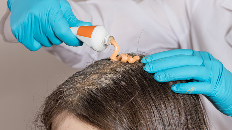 trichologist pouring a paste on a lady's hair