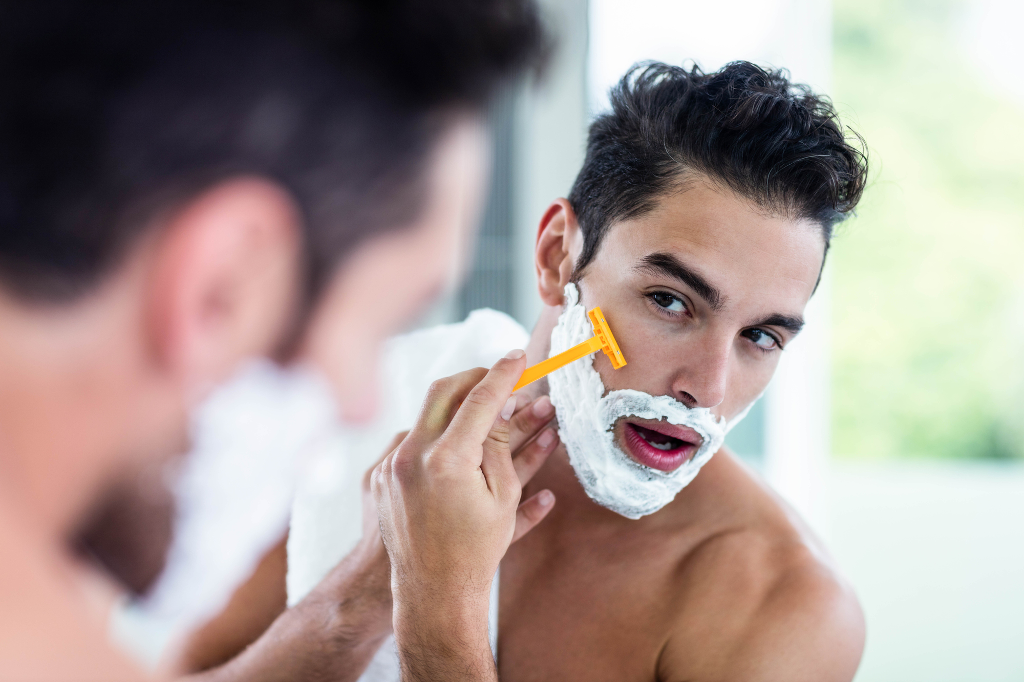 Handsome man shaving his beard in bathroom